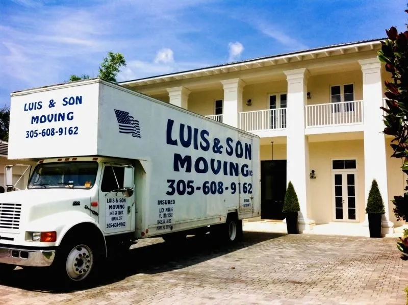 Luis & Son Moving truck in the driveway of a large white two-story home