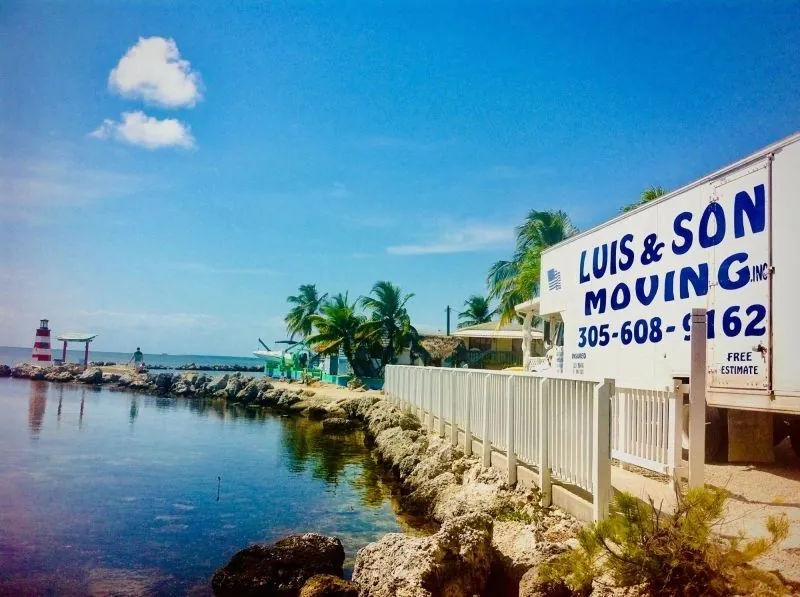 Luis & Son Moving truck at a waterfront home with turquoise water